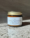 Jar of Natural Northern lavender magnesium cream with a gold lid on a textured surface