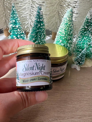 Kim Laureano founder of Natural Northern in Minocqua WI holding a limited edition mini  1oz holiday jar of bestselling magnesium cream in the blend wintergreen and lavender. Magnesium cream is a topical cream applied on the feet, calves, knees, or sore muscles for soothing and calm support. 