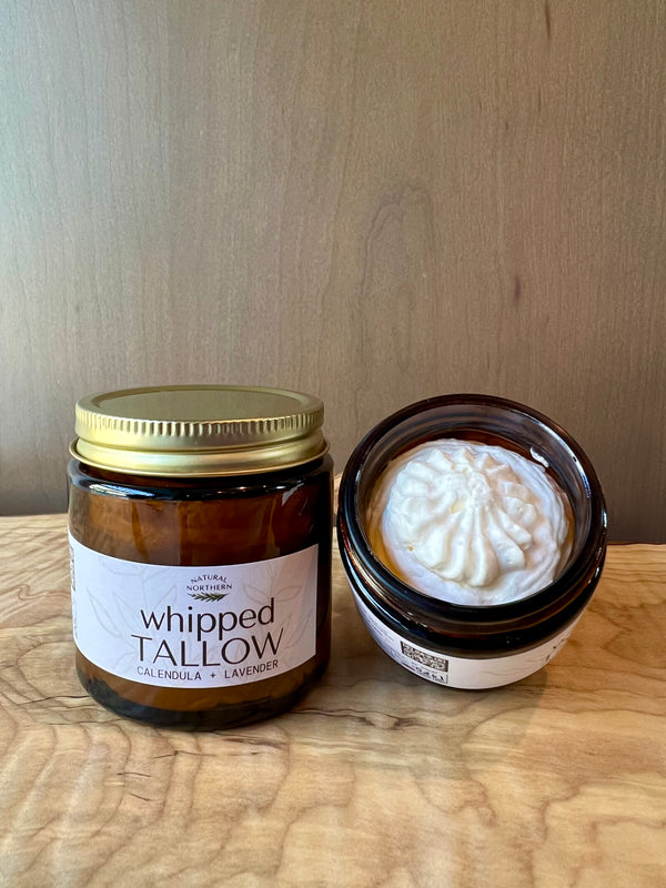 Jar of natural northern whipped tallow with a small container of cream on a wooden surface.