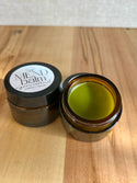 Open jar of Mend balm on a wooden surface. comfrey and tallow balm